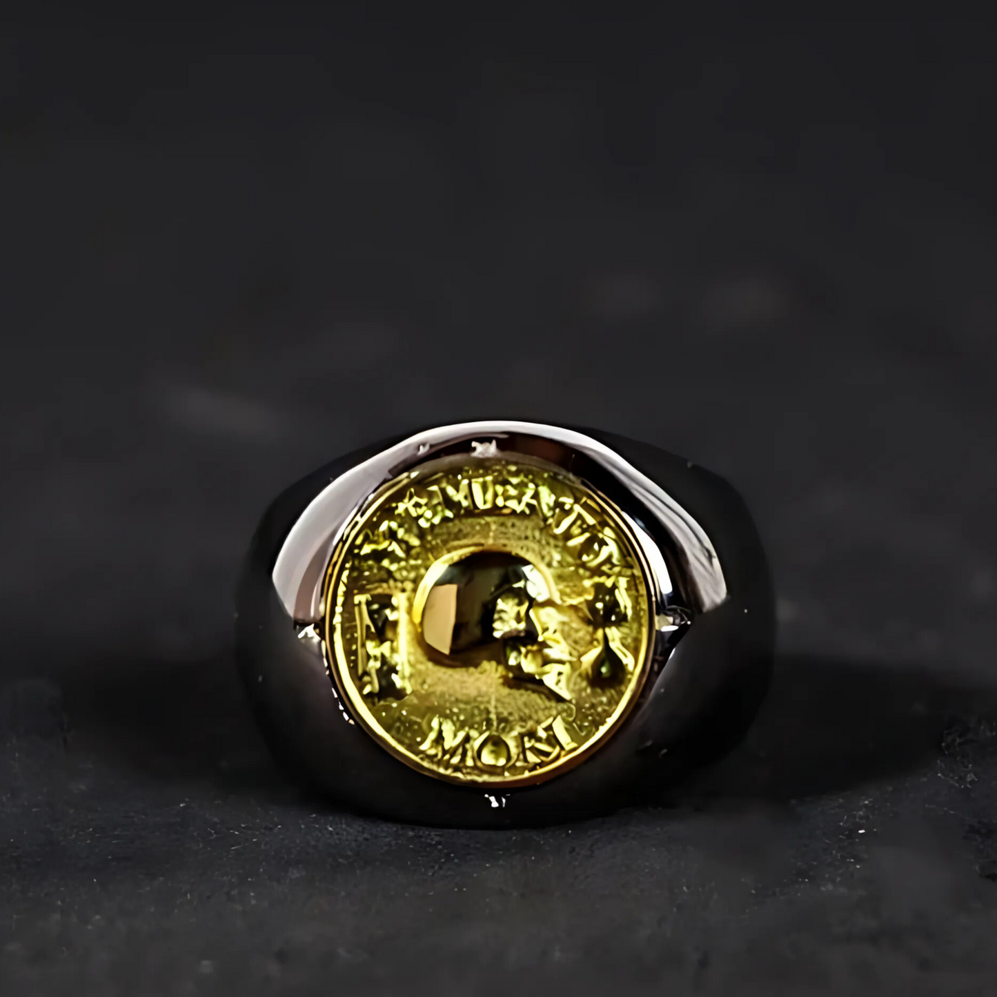 A ring with a gold-colored emblem on it, placed on a dark surface.