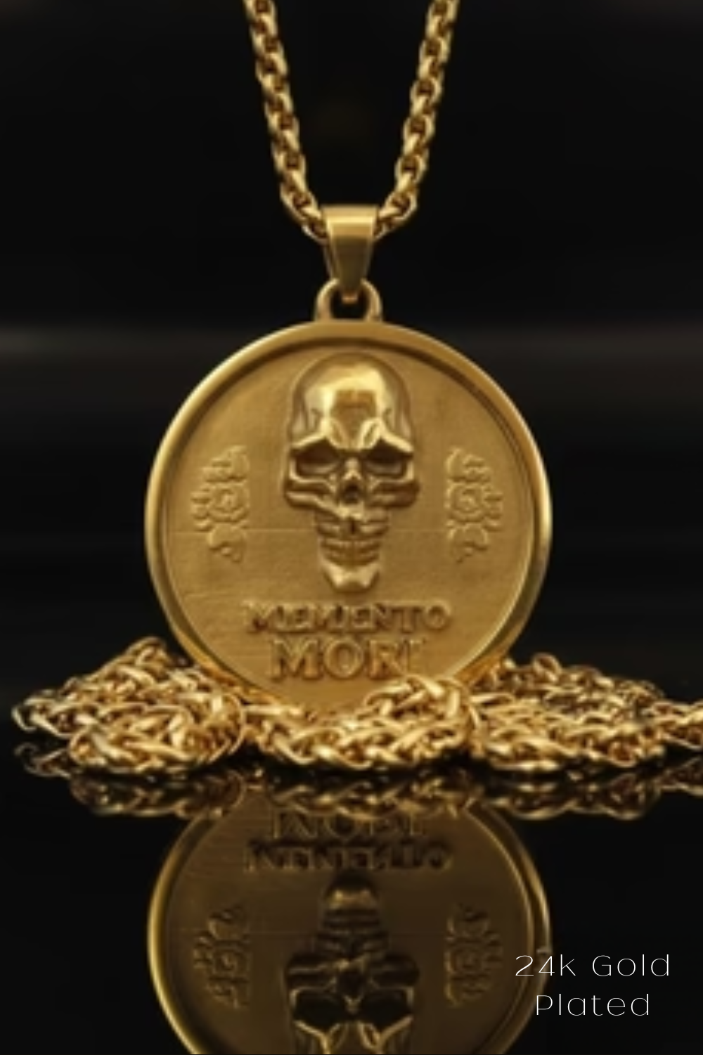 A gold-plated pendant necklace with a medallion featuring a skull design and the Latin phrase "Memento mori" engraved on it.