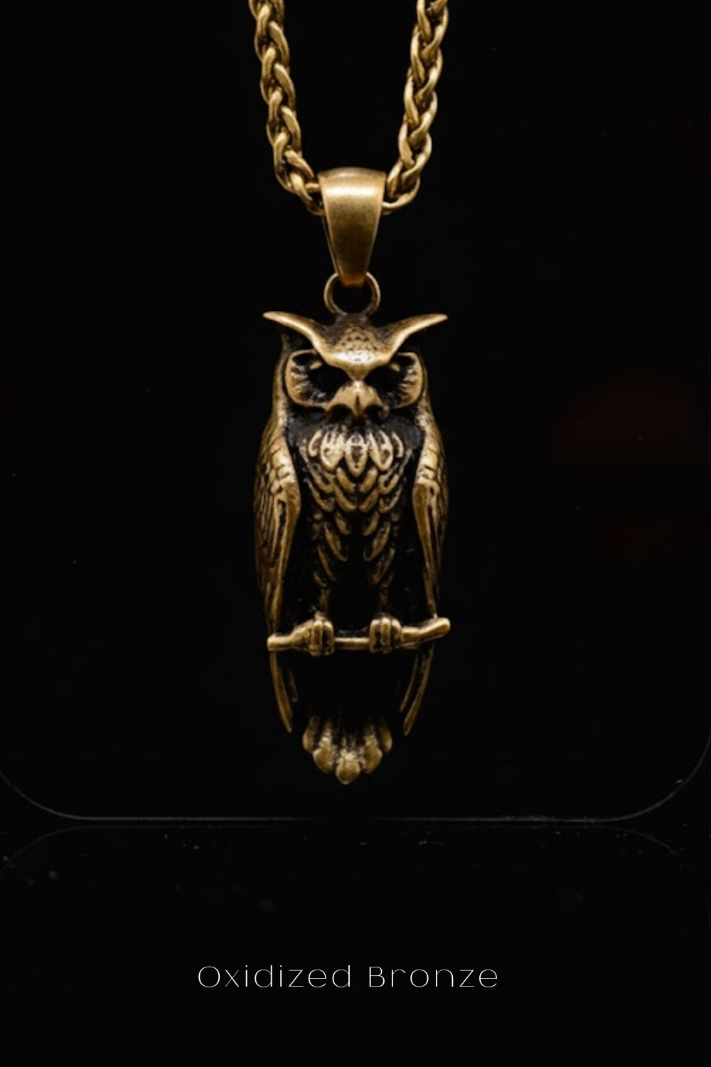 A gold-colored pendant in the shape of an owl, with intricate details and a chain-link design.