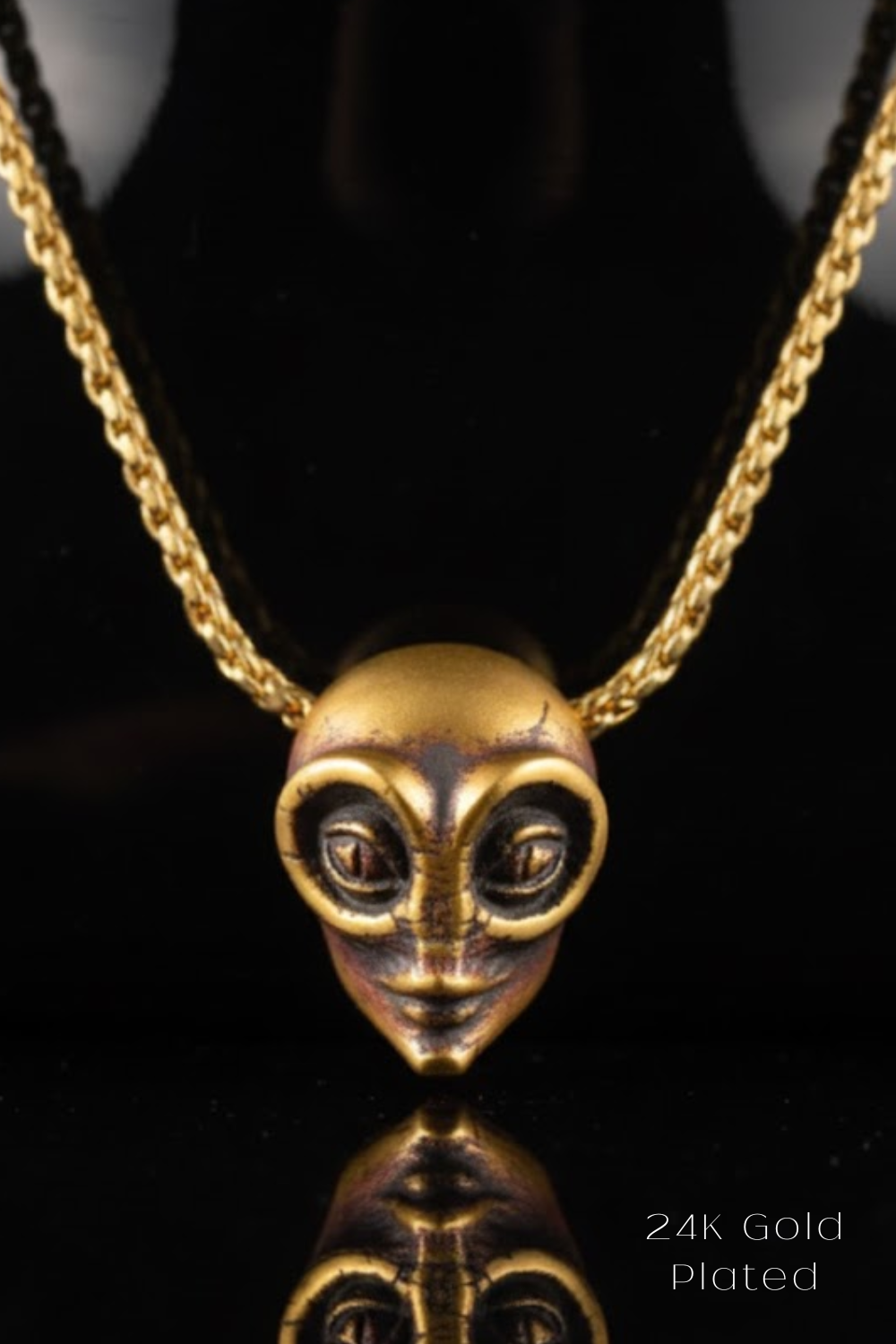 A 24K gold-plated pendant necklace with a unique alien-like face design.