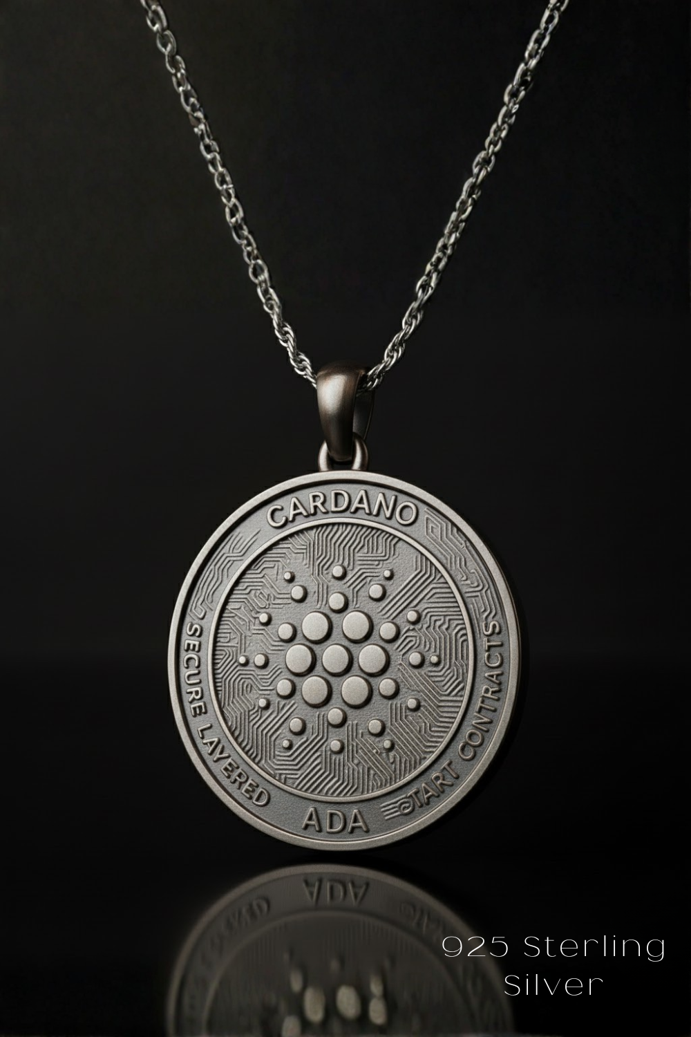 A silver pendant necklace with a circular medallion featuring the Cardano token design.