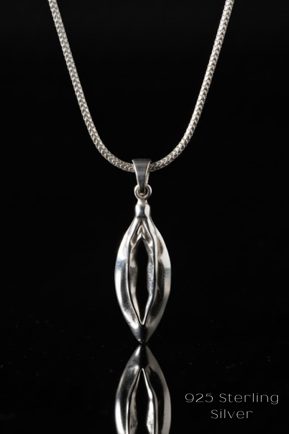A silver necklace with a pendant featuring a unique, abstract design.