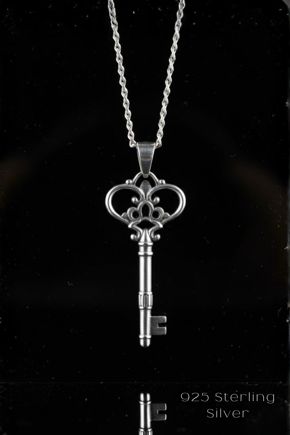 A silver-colored key pendant necklace against a black background.