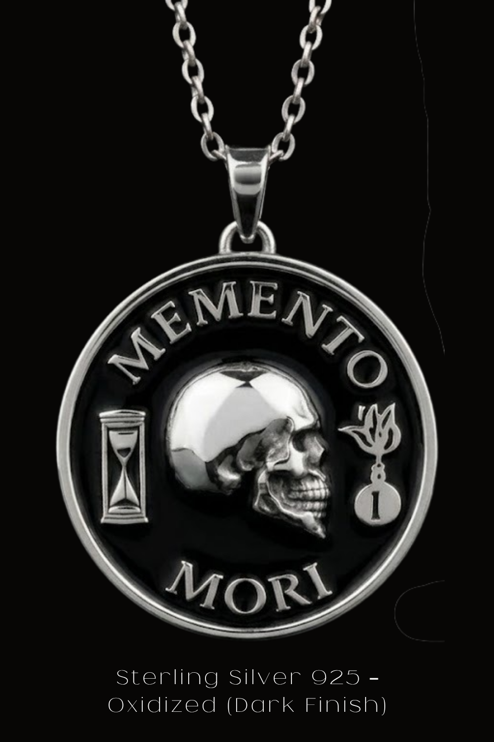 A silver pendant necklace with a circular design featuring a skull, a sand timer, and the Latin phrase "Memento mori" (which means " remembrance of death ").