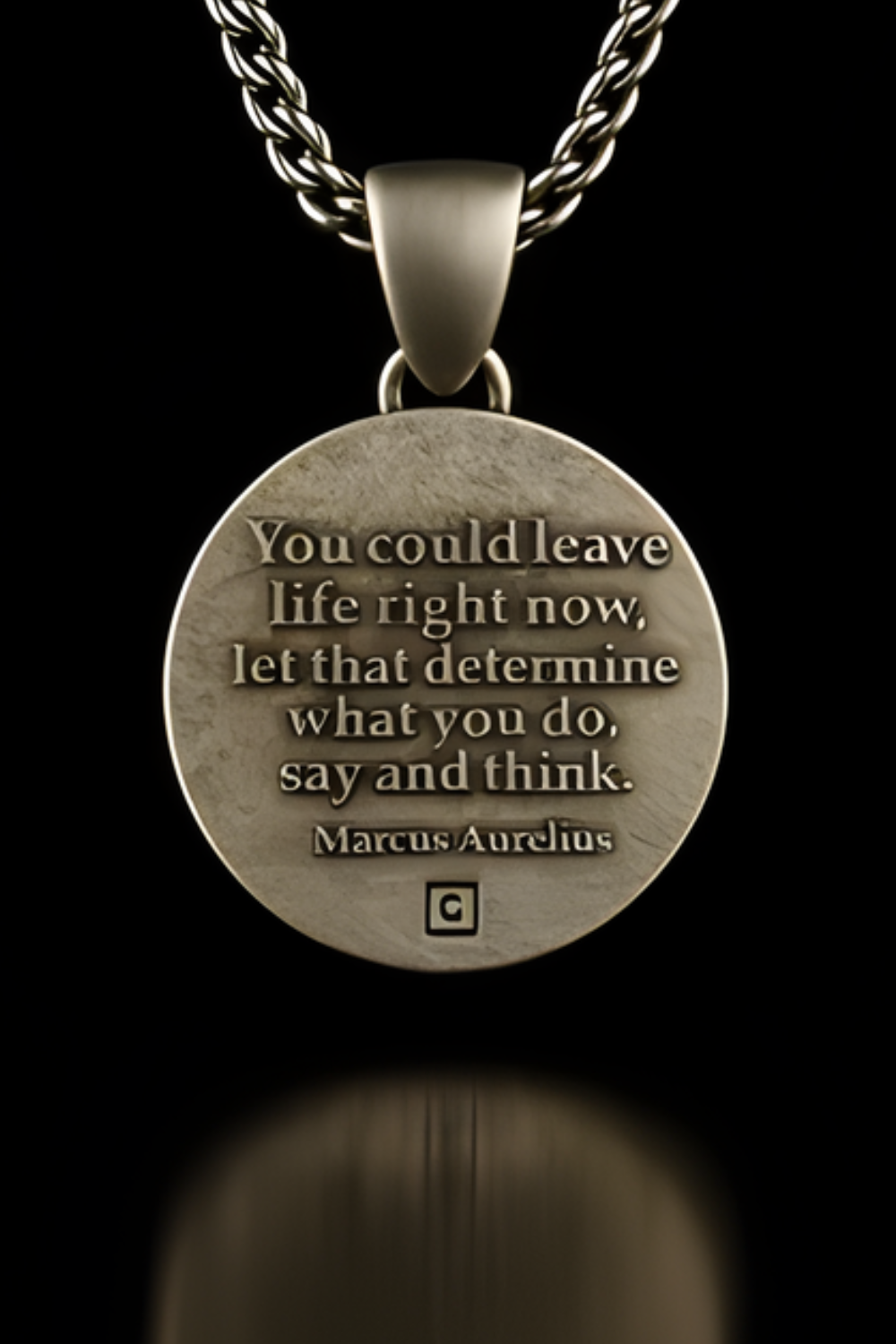 A silver-colored pendant necklace with a circular medallion featuring a motivational quote by Marcus Aurelius.