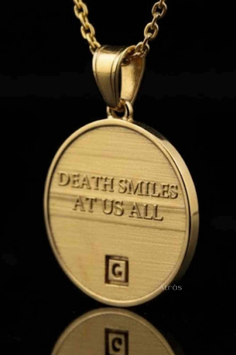 A gold-colored pendant necklace with the text "DEATH SMILES AT US ALL" engraved on it.