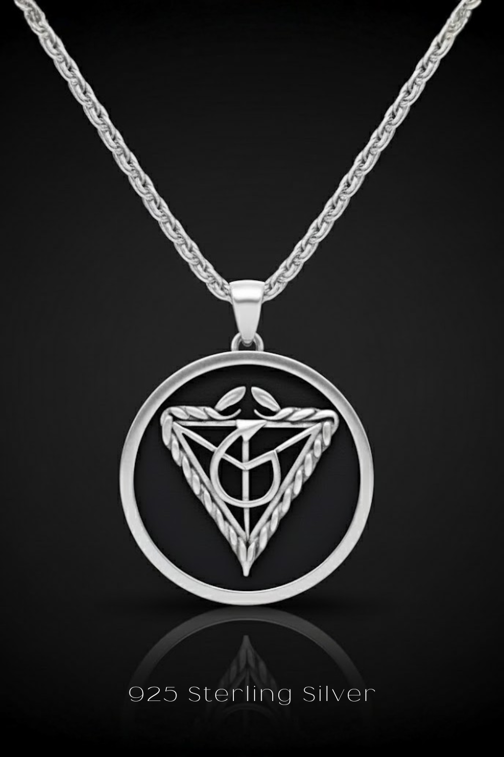 A silver necklace pendant with a circular design featuring a symbol or emblem.