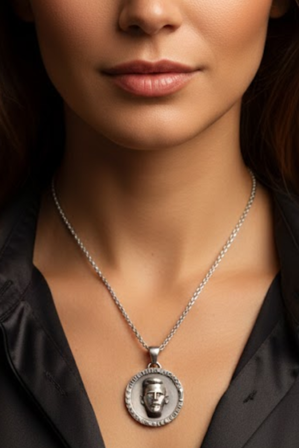 A close-up of a woman's neck and chest area, with a silver necklace featuring a pendant with a portrait of a man's face.