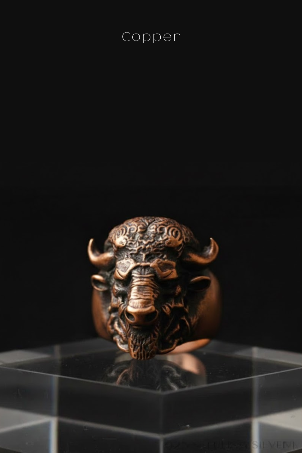 A close-up image of a copper-colored metal ring featuring a detailed, sculpted buffalo head design.