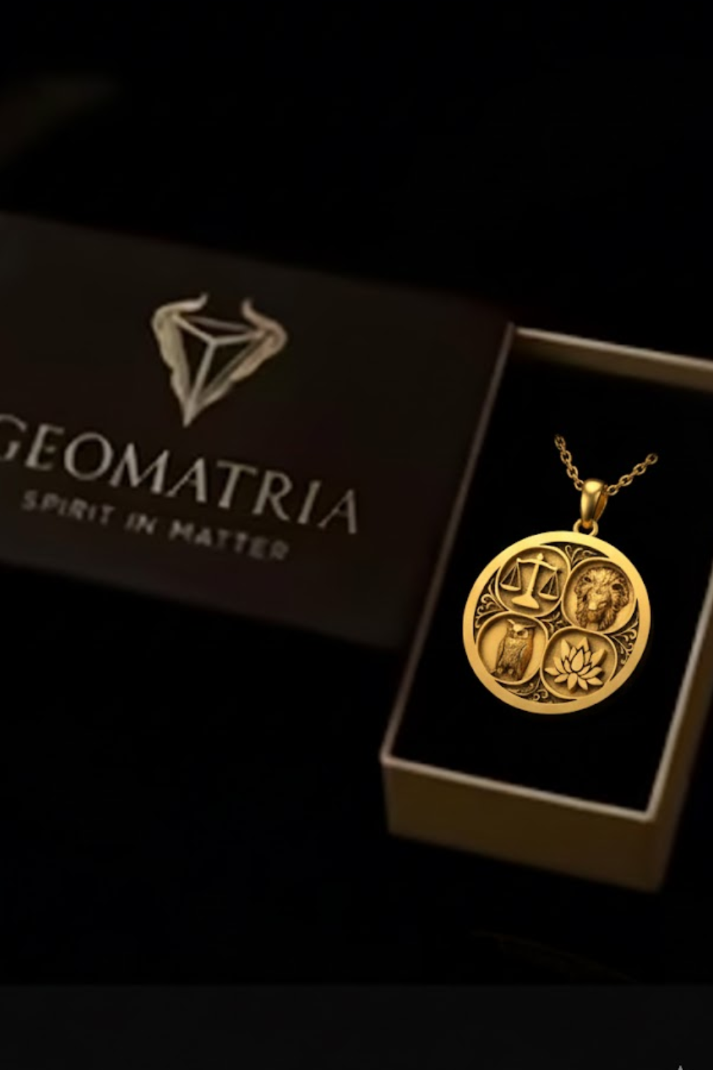 A gold-colored pendant necklace with a circular medallion featuring various symbols, displayed in a black box with the Geomatria logo.