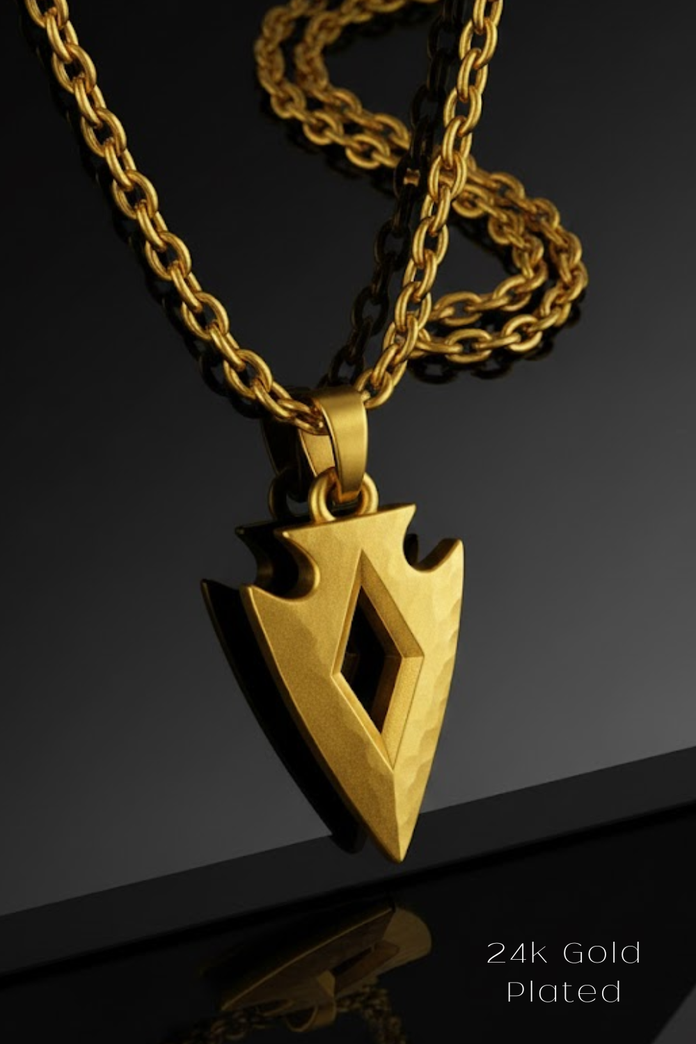 A gold-plated pendant featuring a diamond-shaped arrowhead design is displayed against a black background.