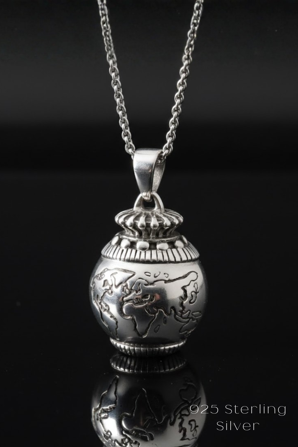 A silver-toned pendant necklace with a globe-shaped pendant featuring a detailed world map design.