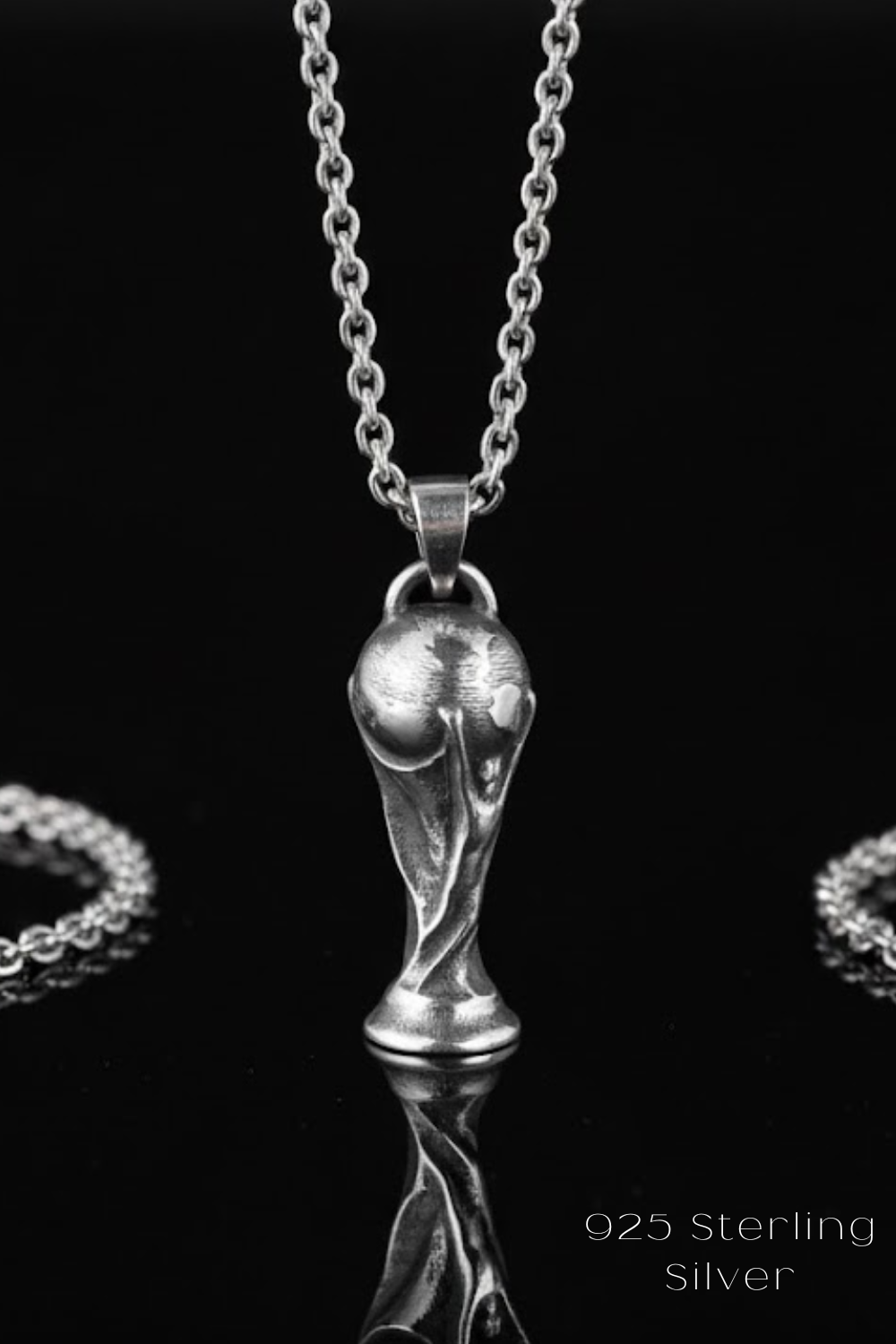 A silver pendant necklace with a trophy-shaped pendant is displayed against a black background.