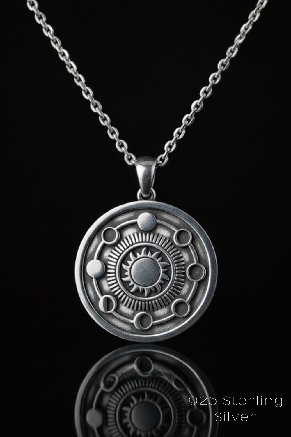 A silver pendant necklace with a circular medallion featuring a sun design and celestial elements.