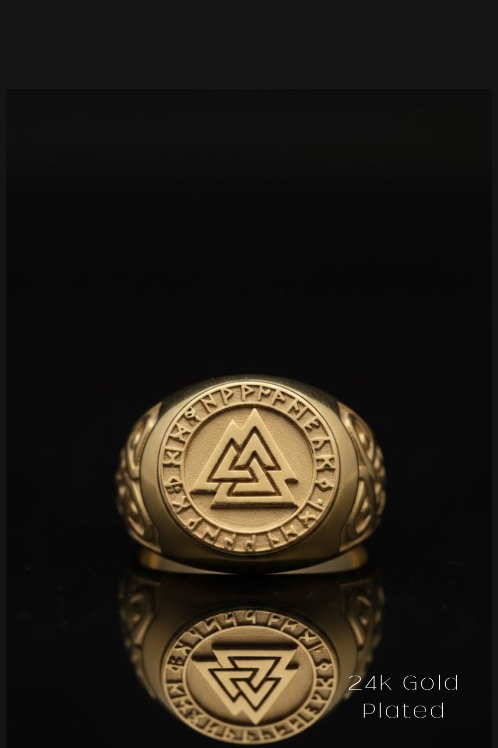 A gold ring with a circular emblem featuring a triangle and a symbol, placed on a reflective surface against a black background.