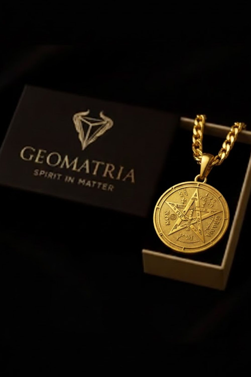 A gold-colored pendant with a pentagram design is displayed in a black box with the text "Geomatria" and "SPIRIT IN MATTERS" printed on it.