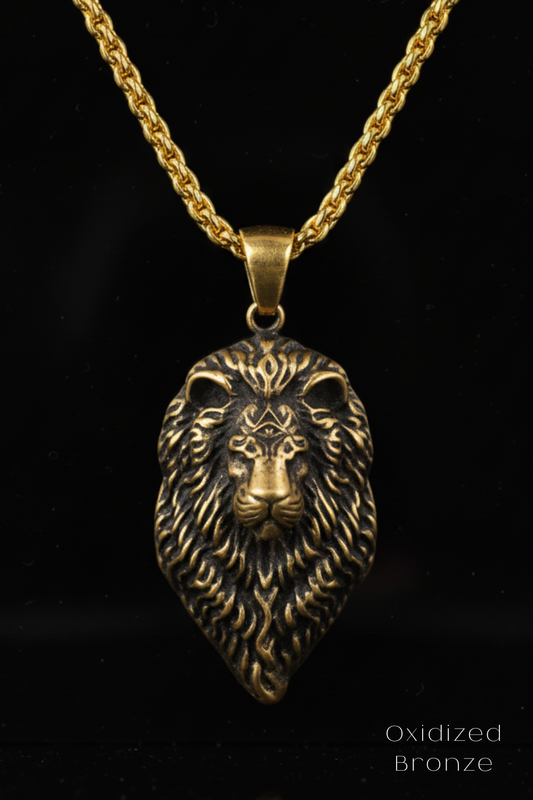 A gold-colored pendant in the shape of a lion's head, with intricate details and a chain around it.