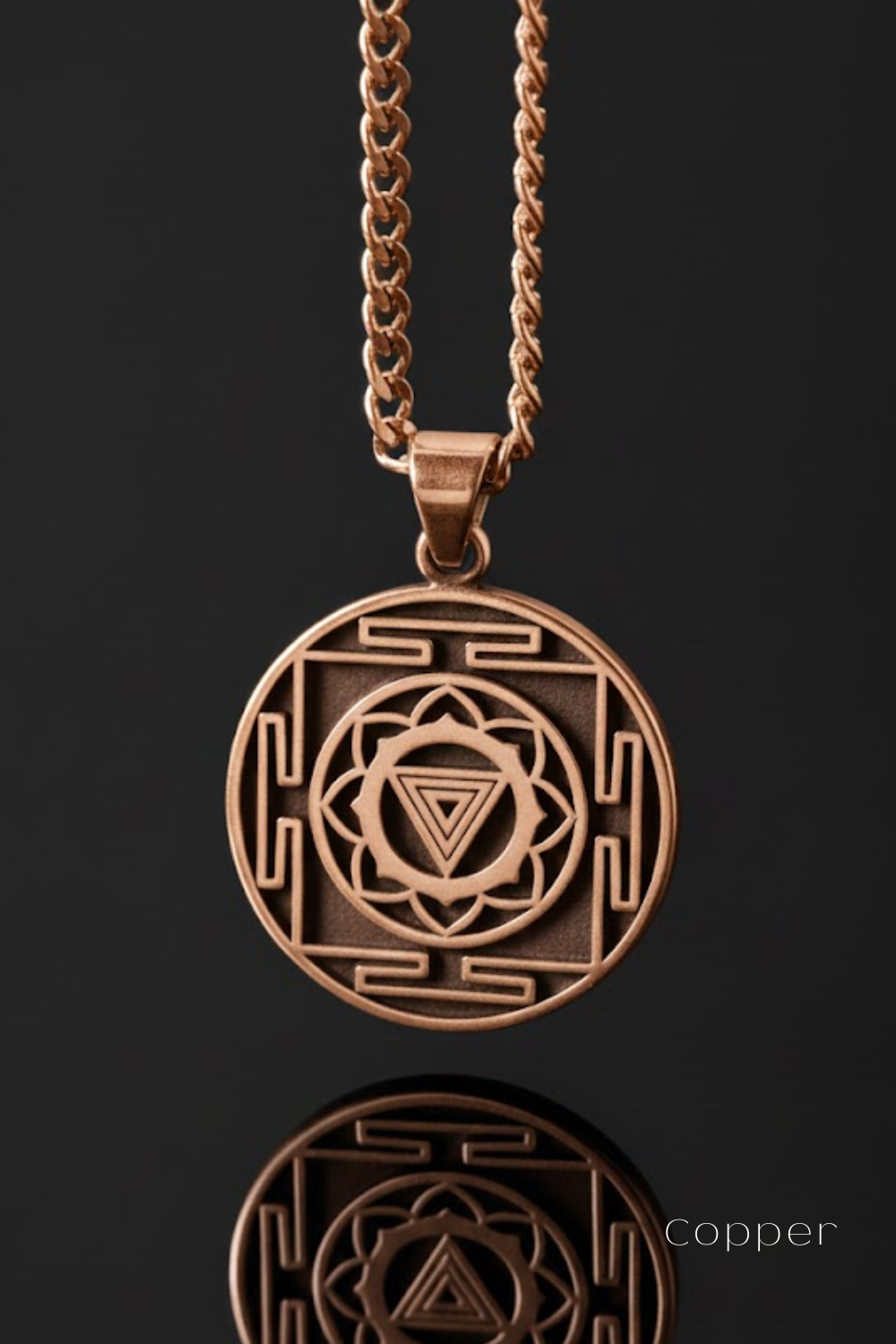 A copper-colored pendant necklace with a circular medallion featuring a geometric design and a triangle symbol.
